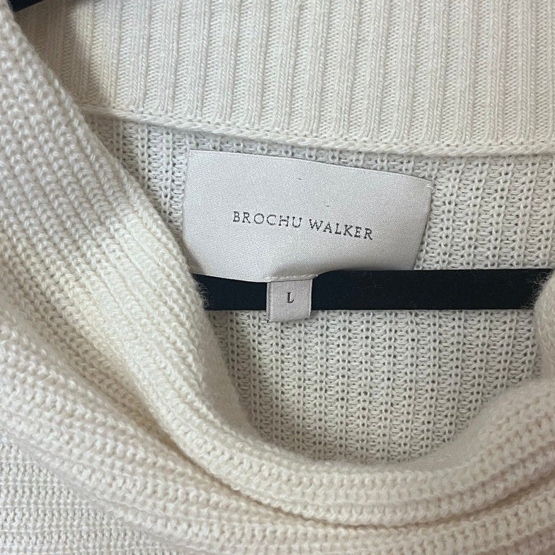 White sweater on a hanger with a brand label visible