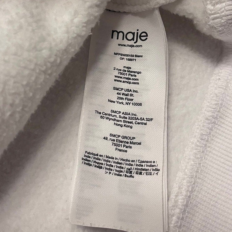 Close-up of a Maje label on a textured fabric background