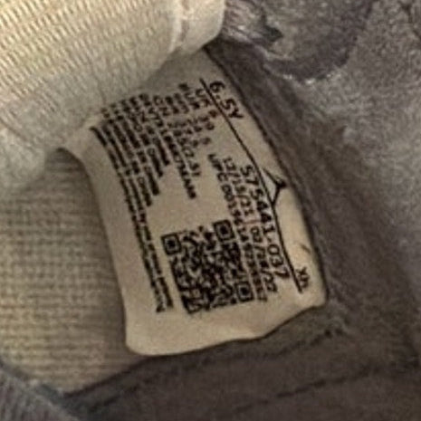 Close-up of a label on a gray shoe with text and a QR code.