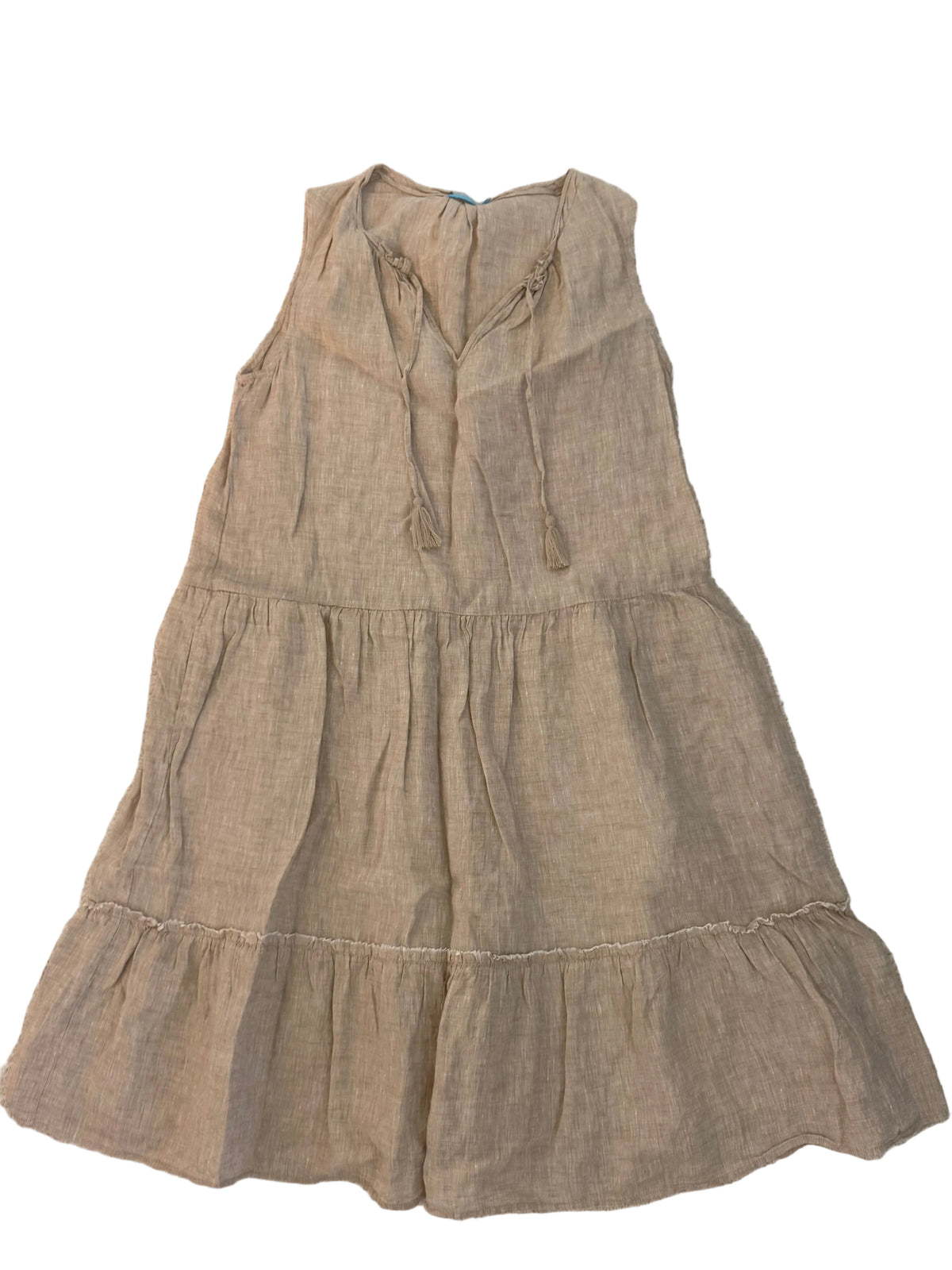 A sleeveless tiered linen dress in a light beige or taupe color, laid flat on a textured off-white fabric background.