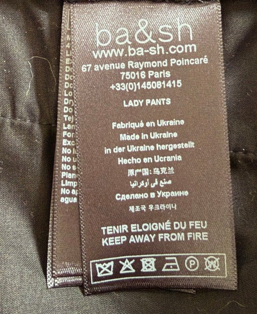 Close-up of a label on a dark fabric, likely a jacket or coat, with visible branding.